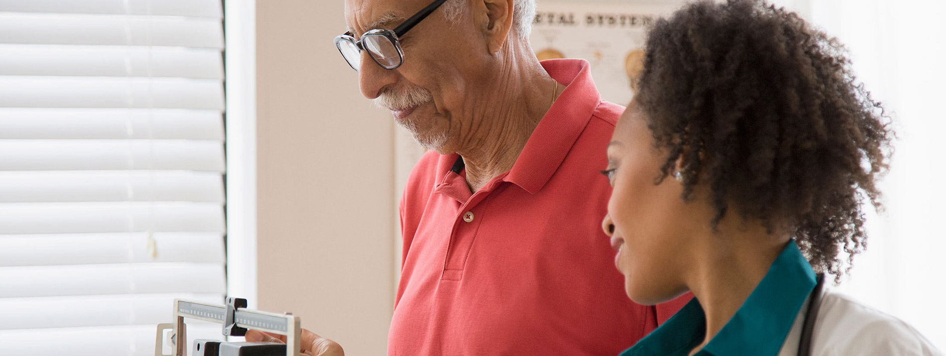 A female doctor taking waist circumference measurements for a male patient.