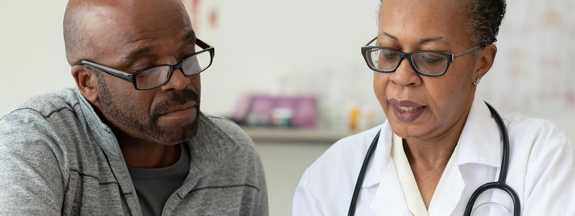 A female doctor and a male patient looking down.