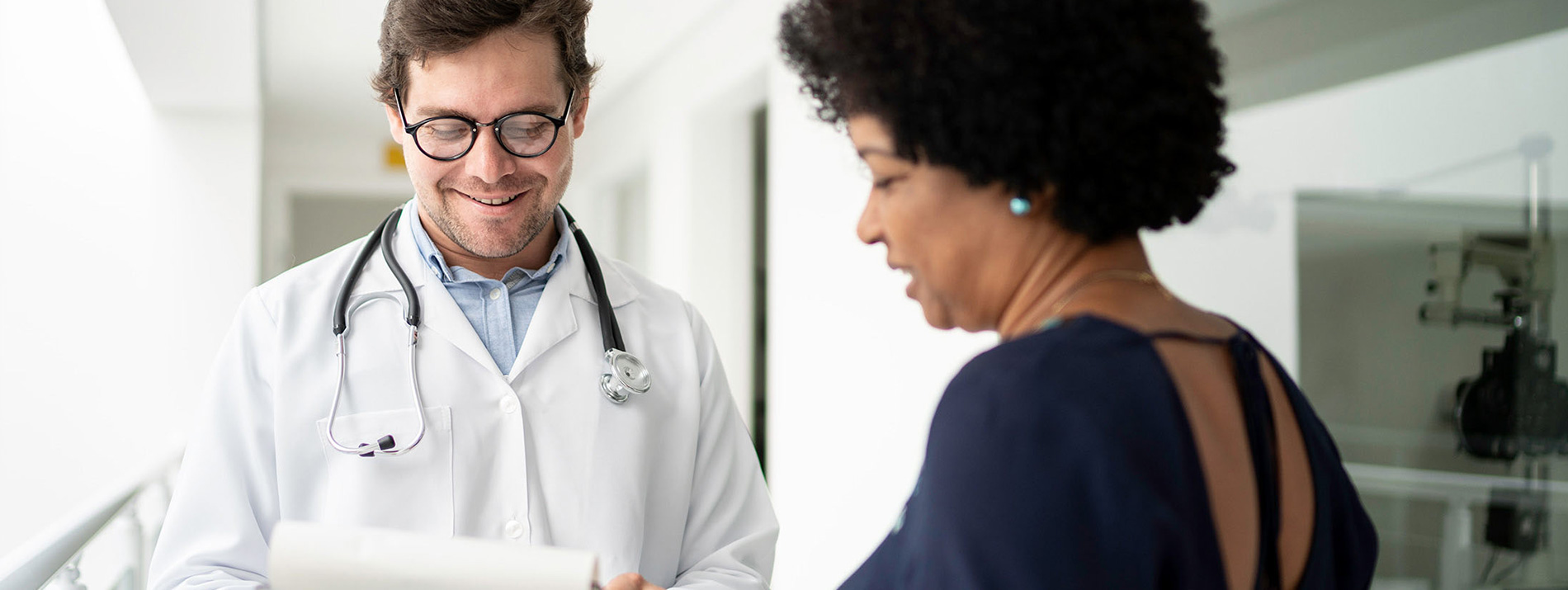 A male doctor looking at a notepad with a woman.