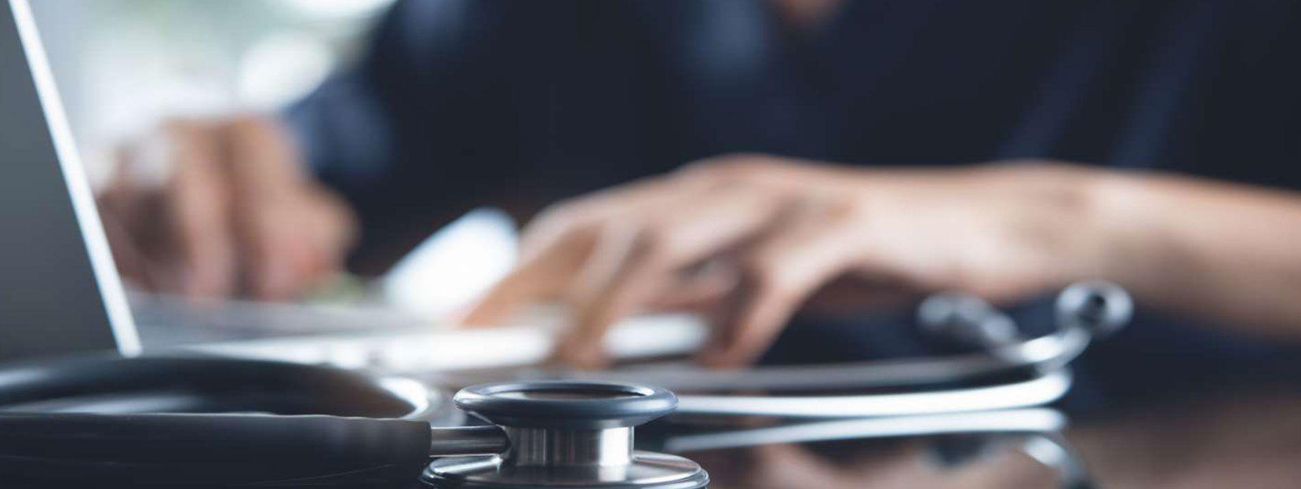 A female doctor typing on a laptop.