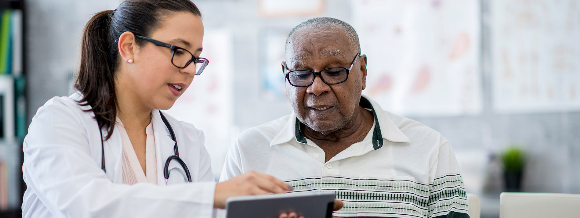 A female doctor showing something on an iPad to a man.